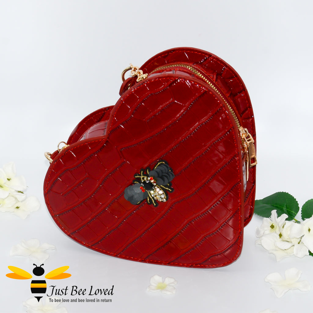 Red faux patent leather heart-shaped handbag featuring embossed crocodile skin, with bee embellishment 