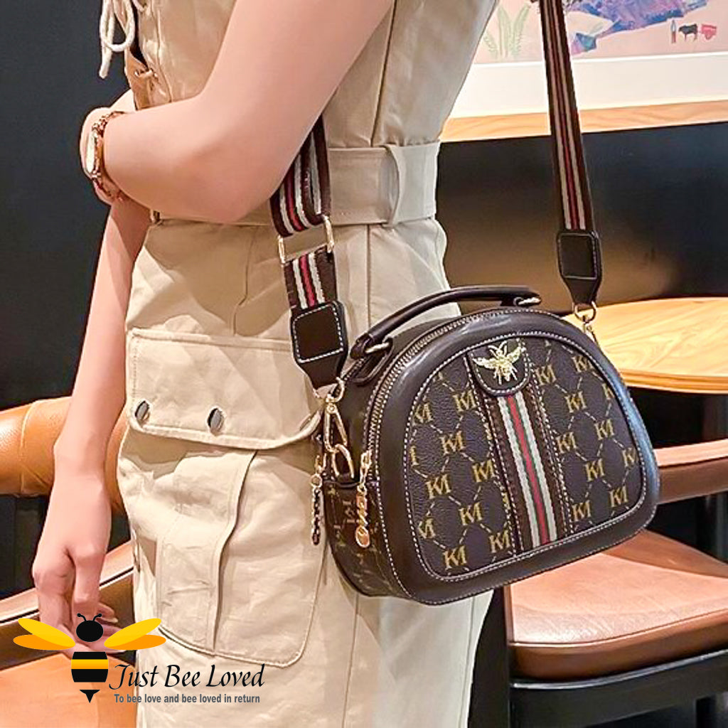 semi-circle crossbody handbag in brown with gold inter-linking letter pattern design with bee embellishment