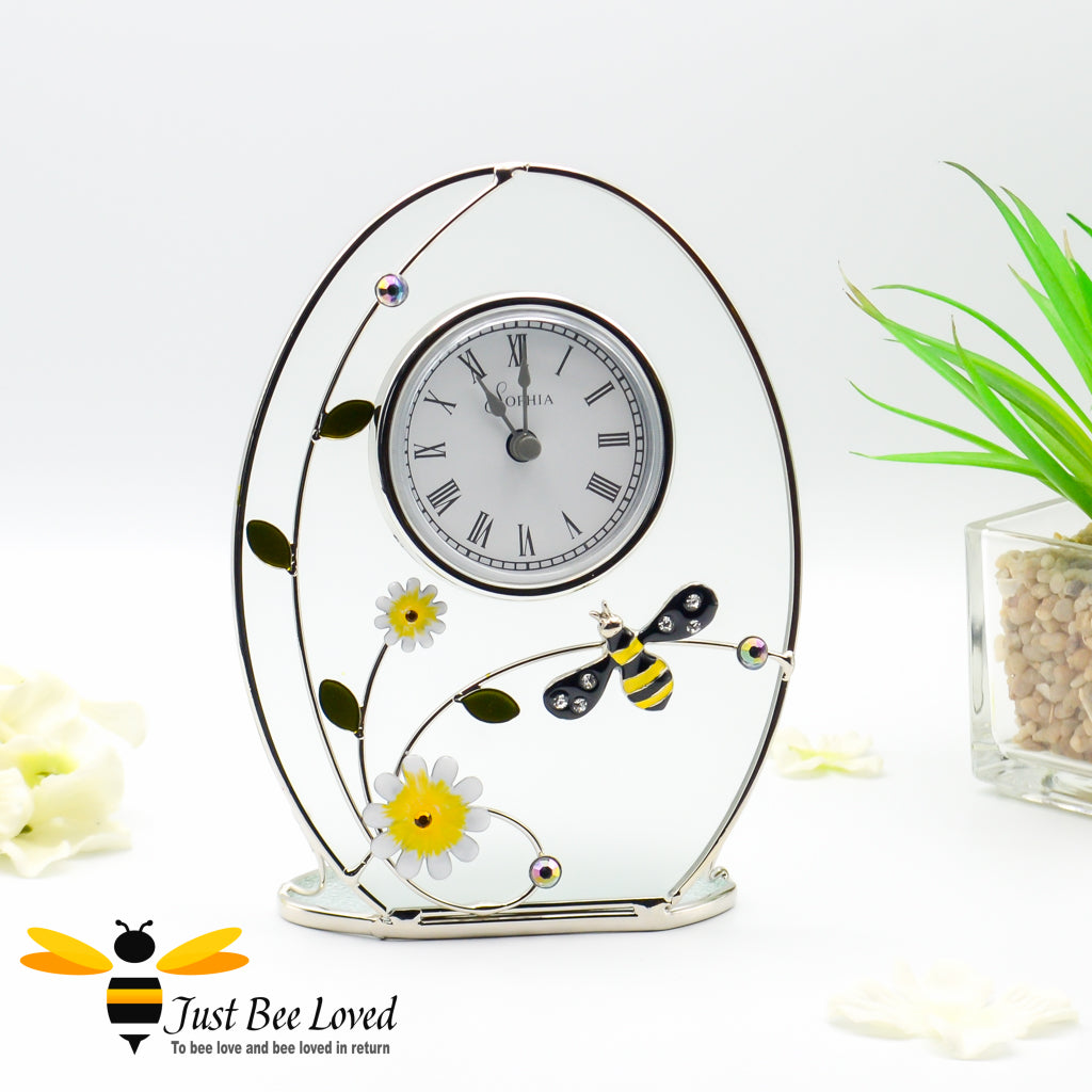 A glass mantel clock with metal wire design featuring a crystal bee and enamelled flowers.