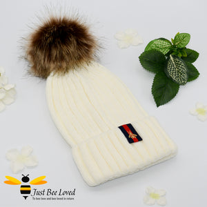 Cream ribbed knit hat featuring a faux fur pom pom with embroidered bumblebee tab on rim