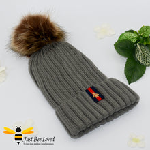 Load image into Gallery viewer, Grey ribbed knit hat featuring a faux fur pom pom with embroidered bumblebee tab on rim