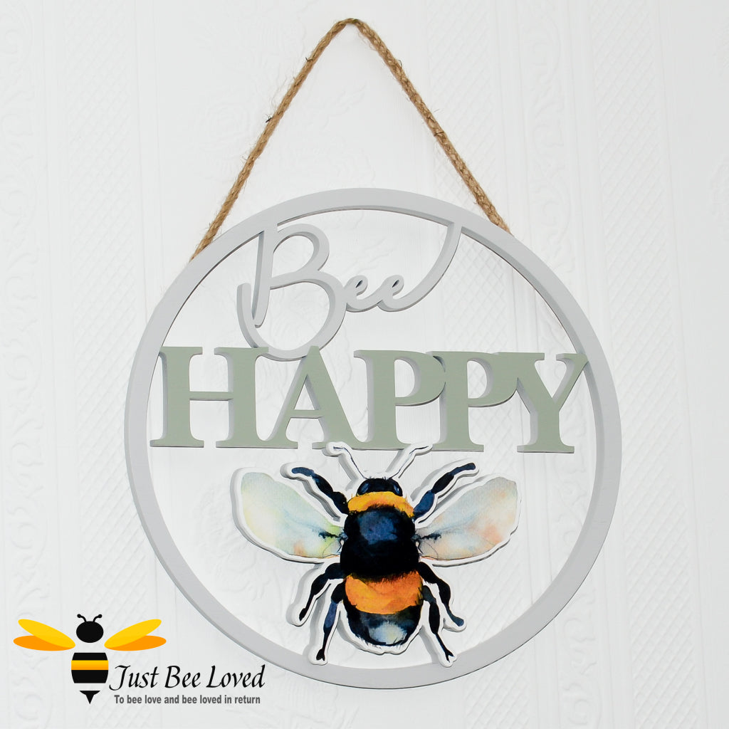 A wooden round hanging plaque with a cut out silhouette of a bumblebee and the message 'Bee Happy' hand-painted in pastel colours.