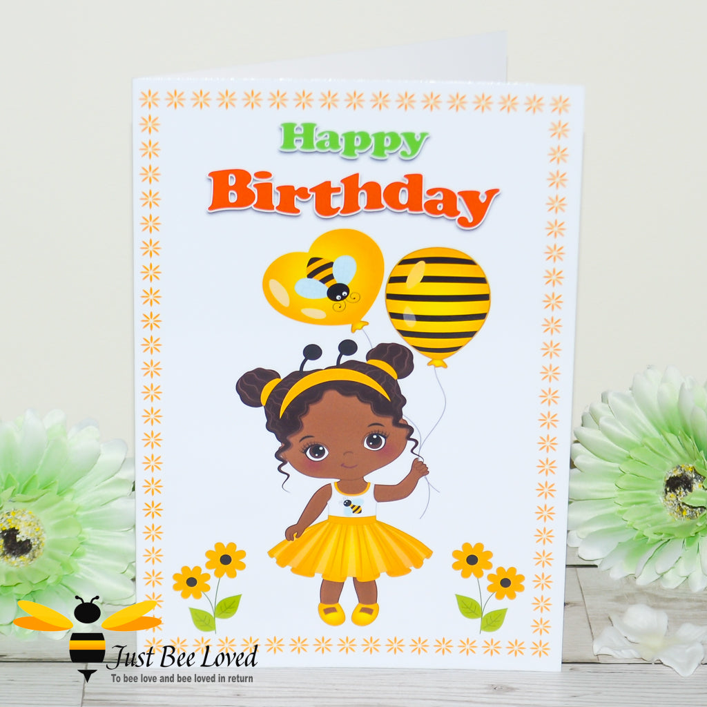 a colourful birthday bee card featuring a cartoon illustration of a young cute black girl dressed in bee clothes and holding bee balloons.  