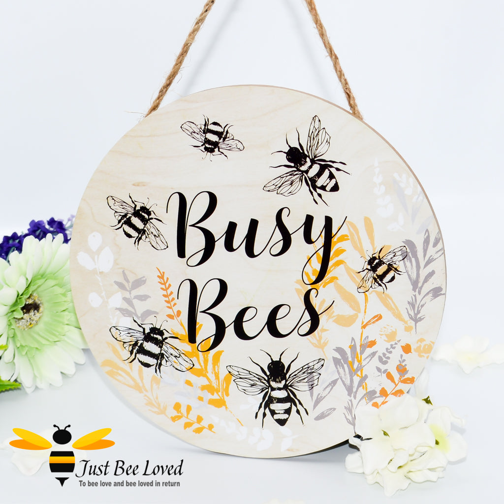 A wooden round hanging wall plaque with the text 'Busy Bees' and illustrations of bumblebees and flowers in a rustic design.