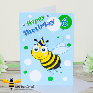 a birthday greeting card for a boy featuring a cartoon bee wearing a party hat, colourful balloons and the number 6.