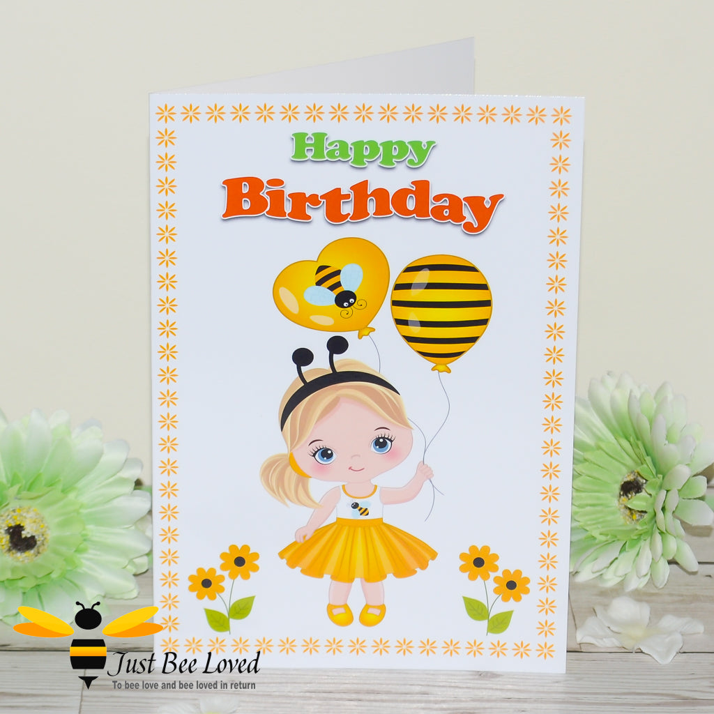 a birthday bee card featuring a cartoon illustration of a young girl wearing bee themed clothes and holding bee ballons, within a frame of daisy flowers.
