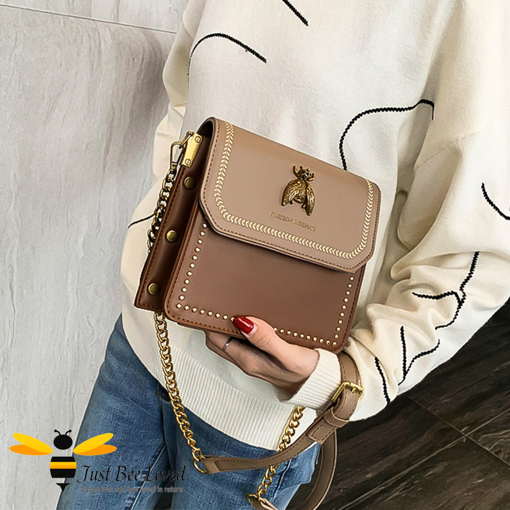 two-tone brown PU with large vintage gold bee embellishment, contrasting cream stitching, gold side studs with matching strap of part leather and gold chain.