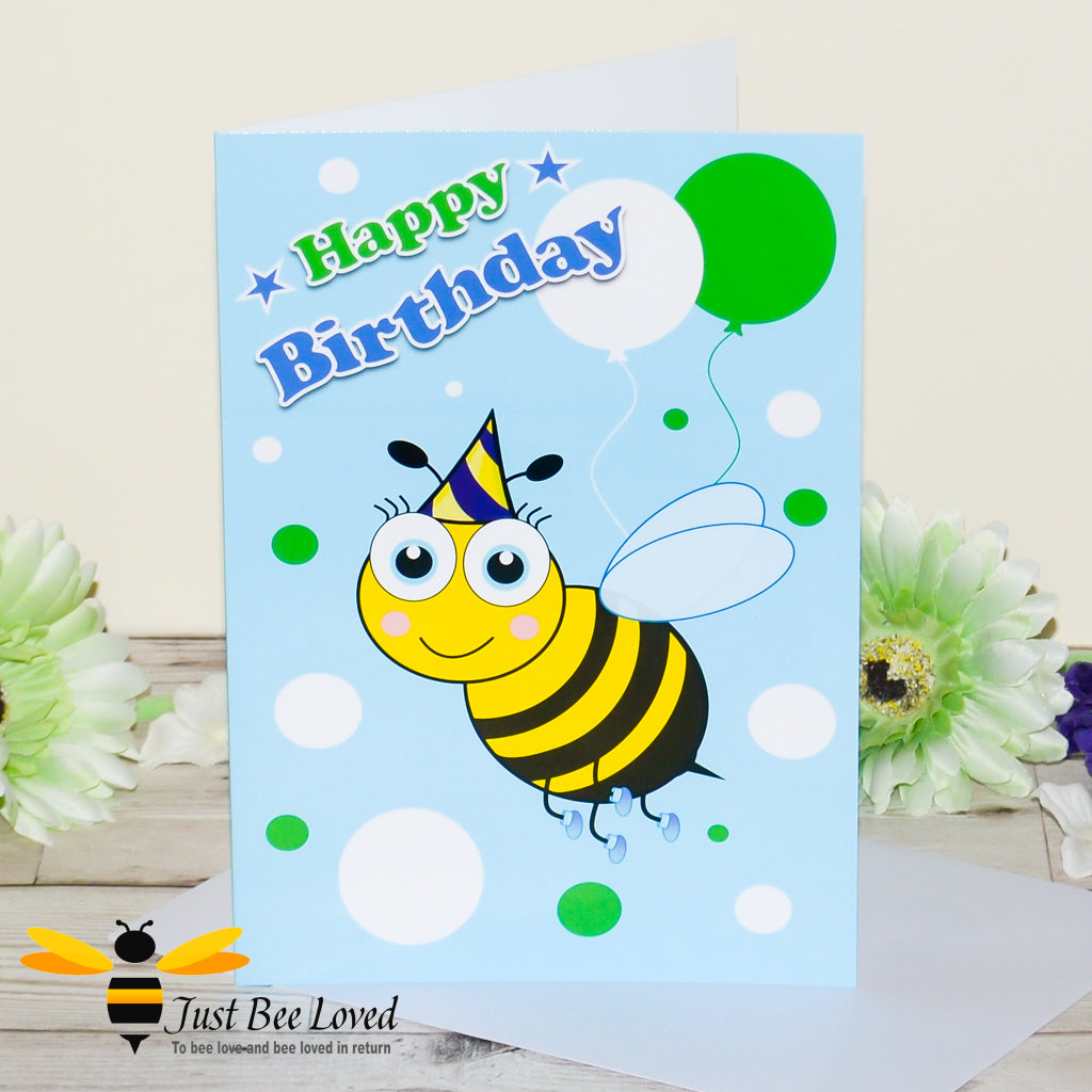a blue birthday bee card featuring a cartoon illustration of a young bee wearing a blue party hat and holding colourful balloons.