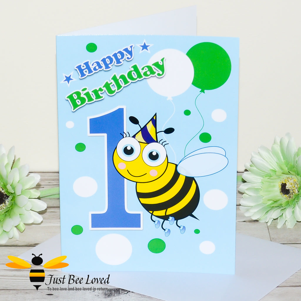 a 1st birthday bee greeting card featuring a cartoon illustration of an infant bee wearing a party hat and holding colourful balloons.