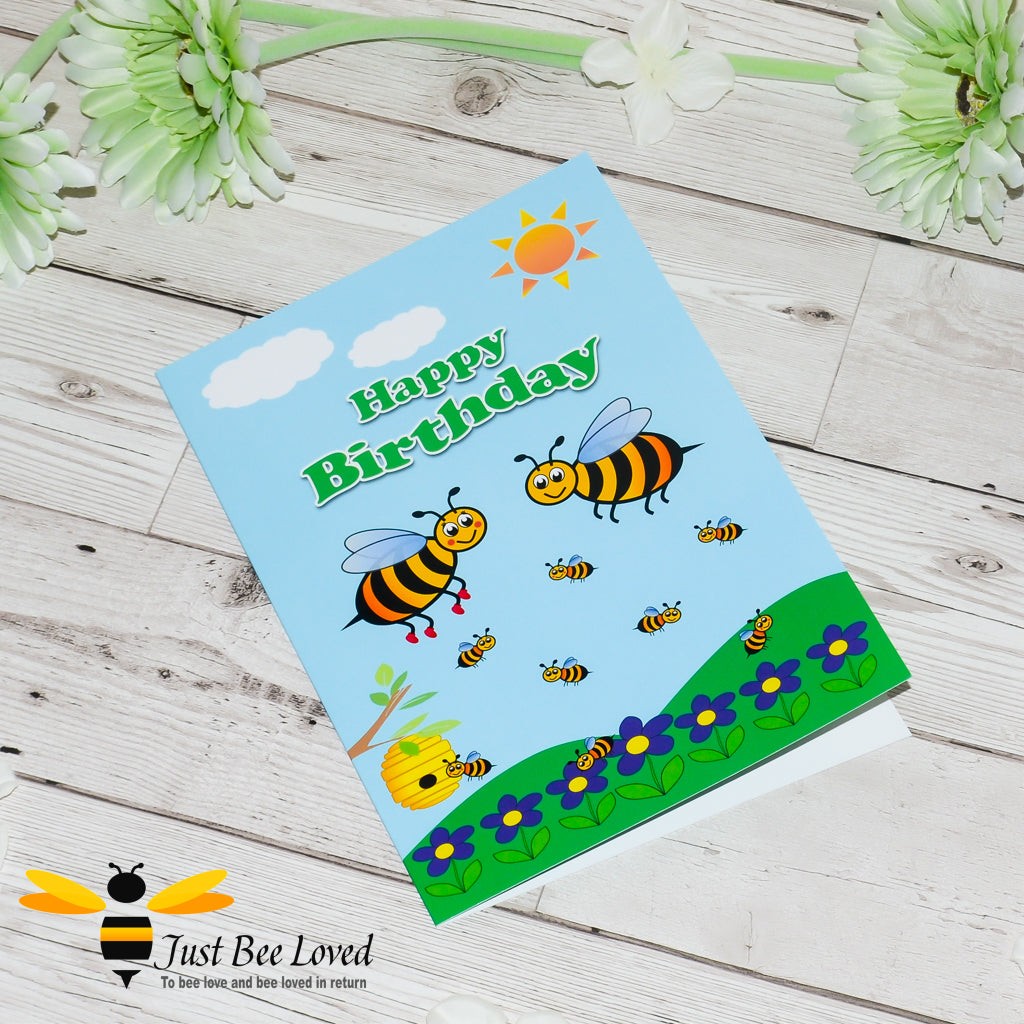 a children's bee themed birthday card featuring a cartoon illustration of a family of bees playing.