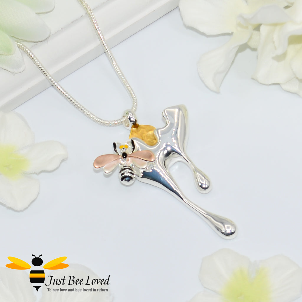 Metallic silver pendant necklace designed to resemble honey drips and pollen with a honey bee motif