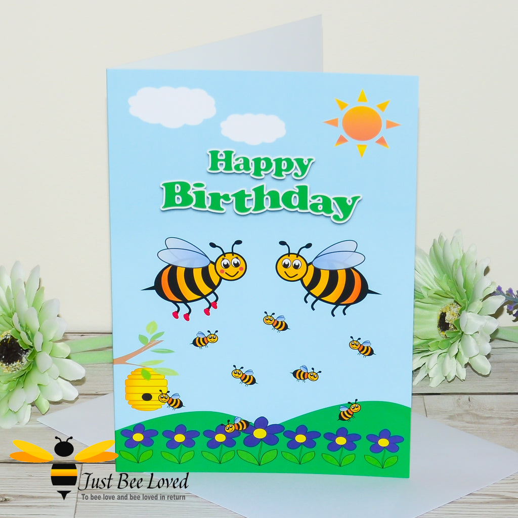 a birthday bee greeting card showing a cartoon illustration of a family of honey bees playing on a blue and green background.