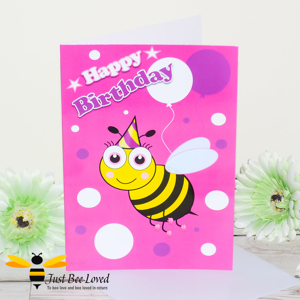 a birthday bee card featuring a cartoon illustration of a young bee wearing a party hat with white and purple balloons on a pink background.